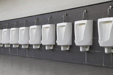 Urinal erkek banyo duvarında yüklü. Beyaz erkek pisuar uzun bir satırda Astarlı.