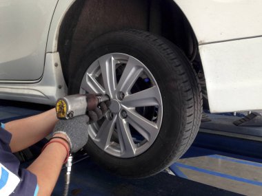 Oto tamircisi direksiyon anahtarı garajda beyaz araba. Mekanik somun makinesi ile tekerlek kaldırmak.