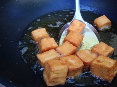 Kızarmış tofu Balık spatula kullanarak sıcak yağ ile bir tavada. Tofu lezzetli bir kızarmış zar.