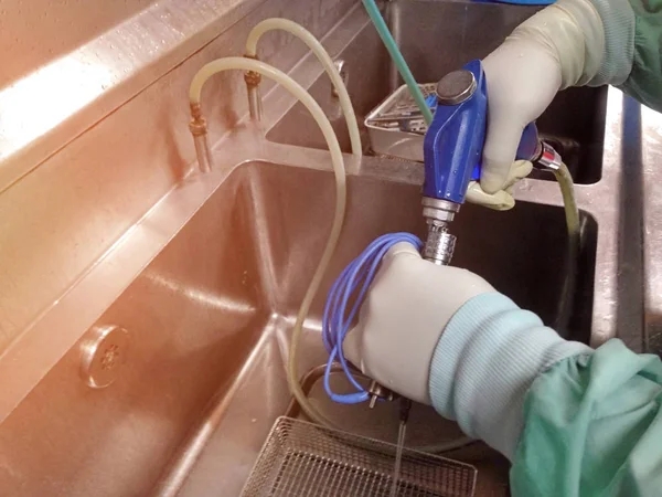 Tıbbi ekipmanları temizleme prosedürü. Basınçla temiz kauçuk tüp için su tabancası. Merkezi Steril Tedarik Departmanı'nda lavabo temizliği.