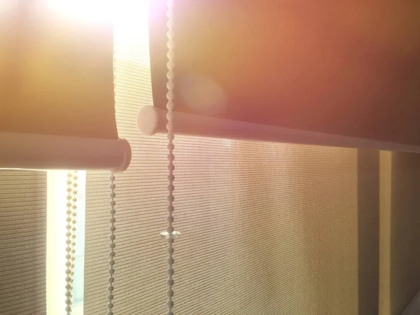 The light shines through the curtain. The light from the outside of the window shines into the  room in the morning.