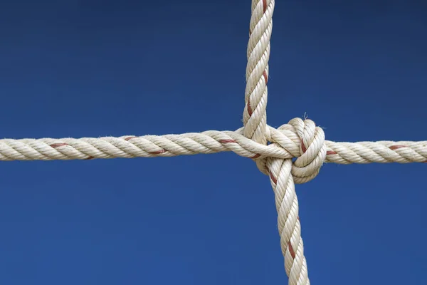 Nylon rope tied into a knot with blue background.