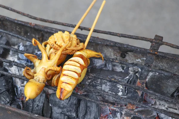 Squid skewer with grilled sticks on a charcoal stove. Grilled squid on a charcoal stove.