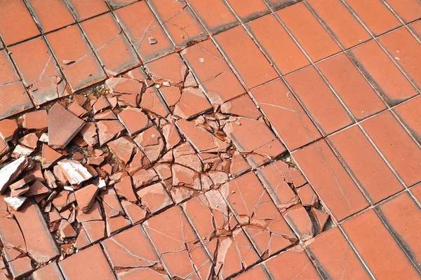 The broken tile floor. Damaged tile flooring caused by impact with heavy objects.
