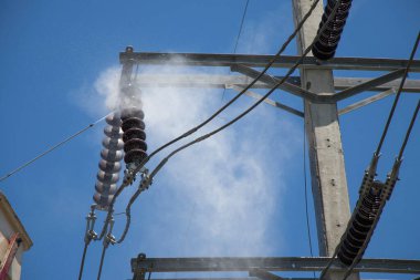 Elektrik idaresi, elektrik direğindeki seramik yalıtıcıyı yüksek basınçlı temizleyicilerle temizliyor..