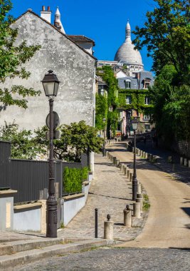 A small street in Montmatre district of Paris with the domes of Sacre Couer in the background clipart
