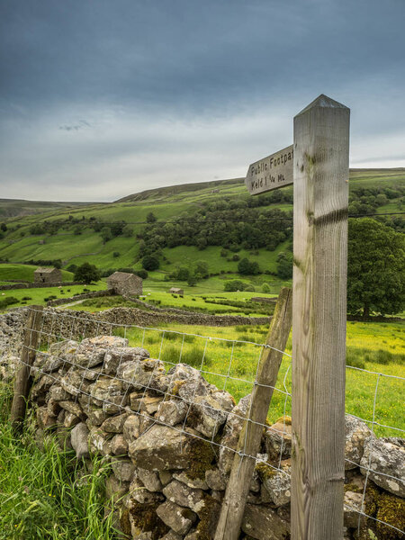 Footpath to Keld in Swaledale, Yorkshire Dales National Park Its upper parts are particularly striking because of its large old limestone field barns , stone walls and its profusion of wild flowers