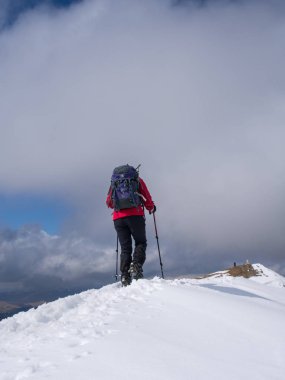 İskoçya'da bir gevrek kış gününde Loch kazanmak, yakınındaki Ben Vorlich zirvesine yaklaşan bir kadın walker