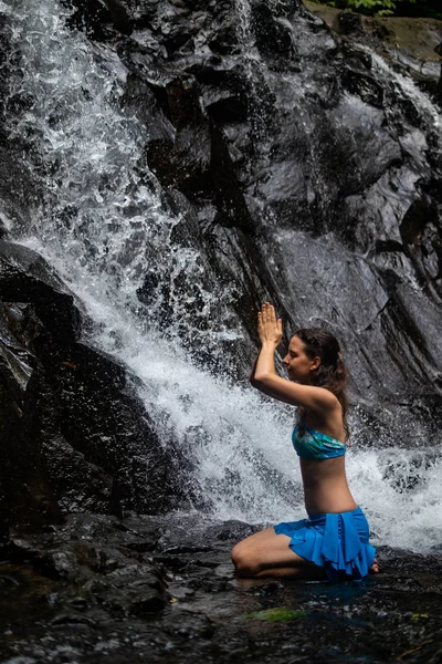 Young Caucasian woman meditating, practicing yoga at waterfall in Ubud, Bali, Indonesia. — Stock Photo, Image