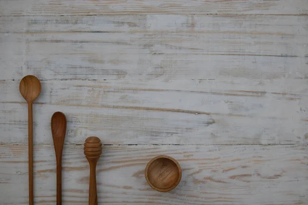 Eco-vriendelijke houten kom, lepels en honing stok op houten tafel achtergrond. Milieuvriendelijk keuken gebruiksvoorwerp plat lag met Kopieer ruimte. — Stockfoto