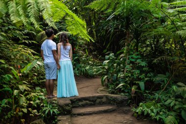 Çok kültürlü çift tropikal ormanda yürüyüş patikadan el tutuyor. Asya 'da tatile genç karışık yarış çift. Ubud, Bali, Endonezya.