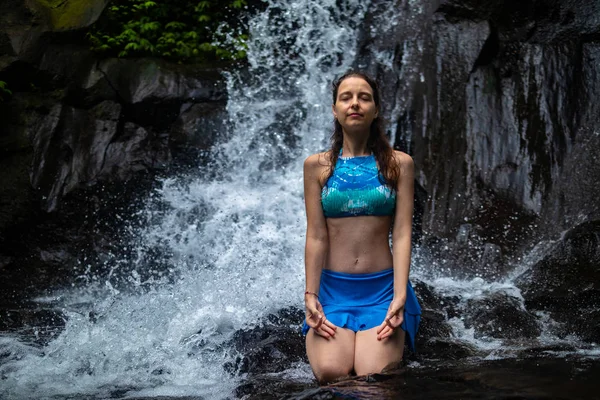 Young Caucasian woman meditating, practicing yoga at waterfall in Ubud, Bali, Indonesia. — Stock Photo, Image