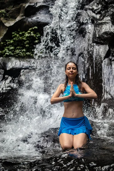 Young Caucasian woman meditating, practicing yoga at waterfall in Ubud, Bali, Indonesia. Close up. — Stock Photo, Image