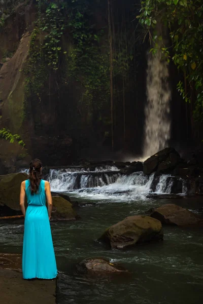Young traveler woman at waterfall in tropical forest, Ubud, Bali. Sumampan waterfall. View from back. — Stock Photo, Image