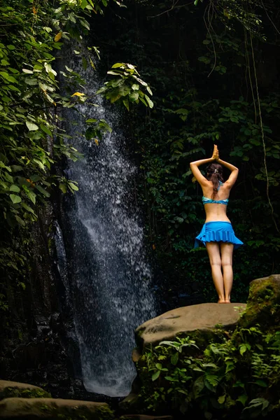 Молода кавказька жінка стоїть на камені, Розмірковуючи, практикуючі йоги на водоспад в Убуд, Балі, Індонезія. — стокове фото
