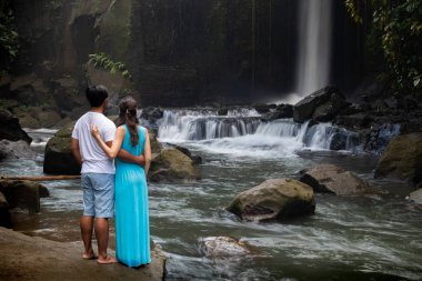 Çok ırklı çift tropikal ormanda şelale yakınında sarılma. Asya'da tatilde genç karışık ırk çift. Arkadan bak. Ubud, Bali, Endonezya.