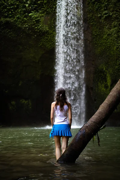 Young traveler woman at waterfall in tropical forest, Ubud, Bali. Tibumana waterfall. View from back. — Stock Photo, Image