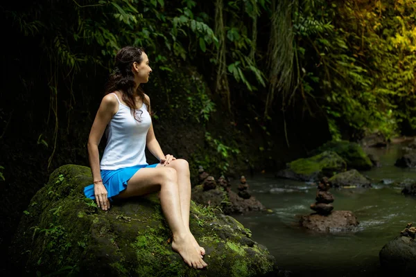 Young Caucasian woman sitting on the rock, enjoying river view — Stock Photo, Image