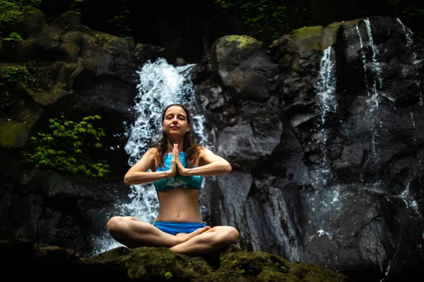 Young Caucasian woman meditating, practicing yoga at waterfall in Ubud, Bali, Indonesia. Close up. — Stock Photo, Image
