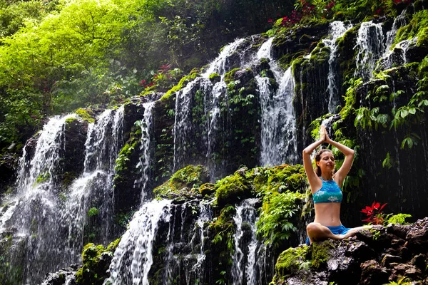 Giovane donna caucasica meditare, praticare yoga a cascata. Vista da dietro. Cascata di Banyu Wana Amertha Wanagiri, Bali, Indonesia . — Foto Stock