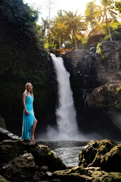 Travel lifestyle. Young traveler woman at waterfall in tropical forest, Ubud, Bali. Tegenungan waterfall. — Stock Photo, Image