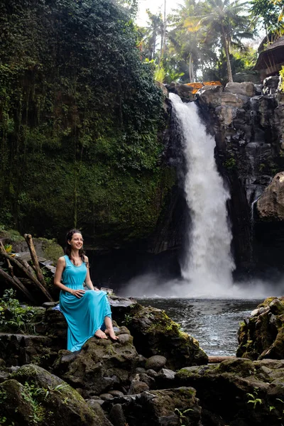 Travel lifestyle. Young traveler woman at waterfall in tropical forest, Ubud, Bali. Tegenungan waterfall. — Stock Photo, Image
