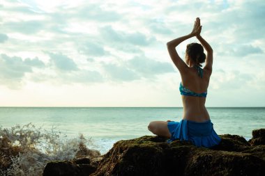 Genç kadın meditasyon, plajda namaste mudra ile yoga ve pranayama pratik, Bali
