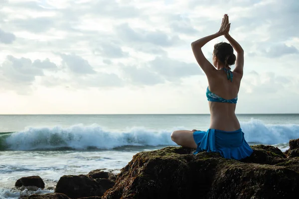 Young woman meditating, practicing yoga and pranayama with namaste mudra at the beach, Bali