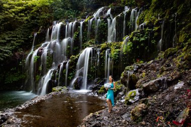 Şelalenin yanında ortanca buket tutan genç bir kadın. Güzel mavi ortanca çiçekler. Düğün öncesi photoshoot. Bali