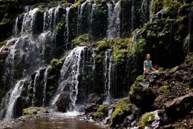 Genç Beyaz kadın meditasyon yapıyor, şelalede yoga yapıyor. Gyan mudra. Banyu Wana Amertha şelale Wanagiri, Bali, Endonezya. 