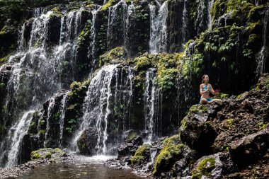 Genç Beyaz kadın meditasyon yapıyor, şelalede yoga yapıyor. Namaste mudra. Banyu Wana Amertha şelale Wanagiri, Bali, Endonezya. 