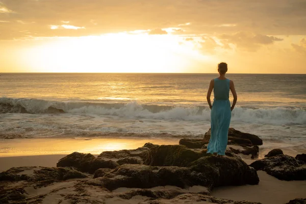 Frau genießt goldenen Sonnenuntergang am Strand. Blick von hinten. — Stockfoto