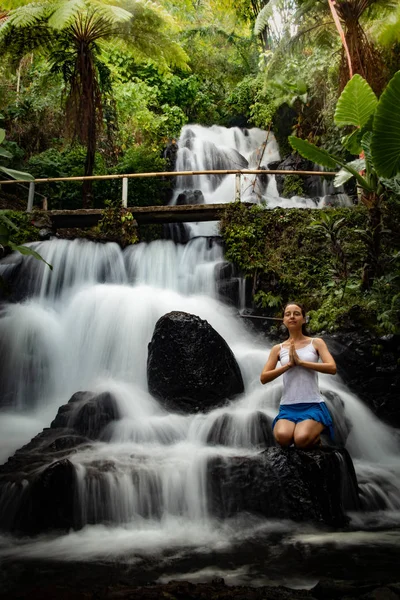 Jeune femme blanche méditant, pratiquant le yoga à la cascade. Namaste mudra. Vitesse d'obturation lente, photographie de mouvement. Cascade de Jembong. Bali, Indonésie — Photo