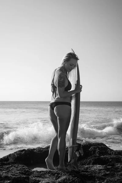 해변에서 서핑 보드와 흑백 서퍼 소녀입니다. 검은 비키니를 입고 젊은 섹시한 여자입니다. 서핑을 준비하는 서퍼 소녀. 발리, 인도네시아 — 스톡 사진