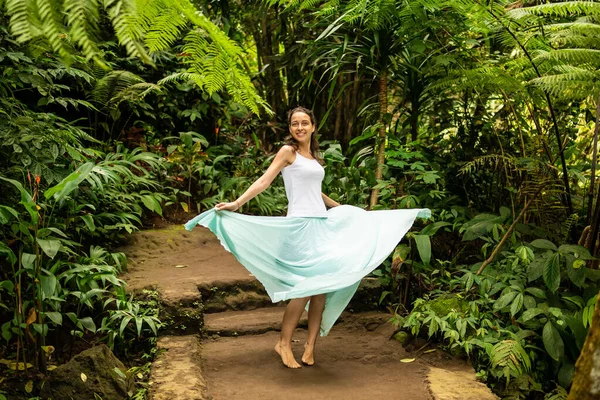 Щаслива молода жінка танцює по стежці тропічного лісу. Подорожуючий спосіб життя. Подорож до Убуда (Балі, Індонезія). — стокове фото