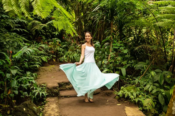 Happy young woman dancing on walking trail in tropical forest. Travel lifestyle. Trip to Ubud, Bali, Indonesia. — Stockfoto