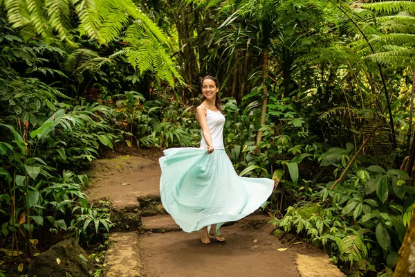 Happy young woman dancing on walking trail in tropical forest. Travel lifestyle. Trip to Ubud, Bali, Indonesia. — Stockfoto