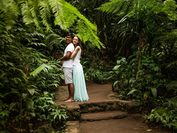 Щасливий усміхнений численне подружжя обійматися на прогулянкові стежки в тропічному лісі. Молоді змішані гонки пара на відпочинку в Азії. Убуд, Індонезія. — стокове фото