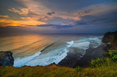 Nefes kesici deniz manzarası. Bali 'deki Uluwatu uçurumundan muhteşem bir manzara. Gün batımı zamanı. Mavi saat. Hareket köpüklü okyanus. Arka plan için su manzarası. Doğa konsepti. Yumuşak odaklanma. Yavaş deklanşör hızı.