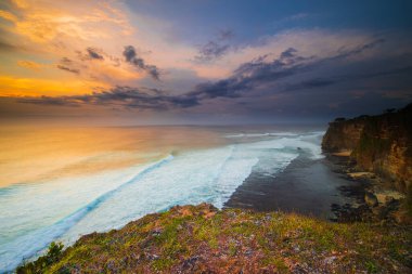 İnanılmaz bir deniz manzarası. Bali 'deki Uluwatu uçurumundan muhteşem bir manzara. Gün batımı zamanı. Mavi saat. Hareket köpüklü okyanus. Arka plan için su manzarası. Doğa konsepti. Yumuşak odaklanma. Yavaş deklanşör hızı.