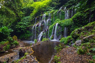 Tropik bir manzara. Yağmur ormanlarında saklı güzel bir şelale. Macera ve seyahat konsepti. Doğa geçmişi. Yavaş deklanşör hızı, hareket fotoğrafçılığı. Banyu Wana Amertha Şelalesi Bali, Endonezya