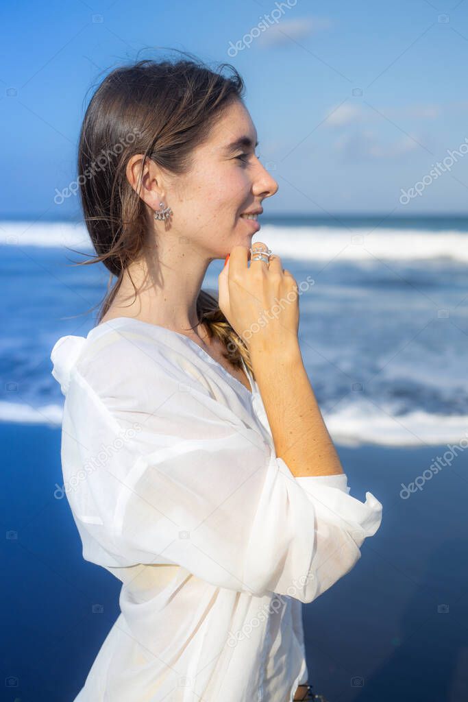 Close up portrait of beautiful woman with jewelry. Caucasian woman enjoying sunlight and looking to the ocean. Beauty and fashion concept. Bali, Indonesia