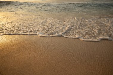 Manzaralı deniz manzarası. Kumsalda köpüklü dalgalar. Gün batımı zamanı. Arka plan için su manzarası. Seçilmiş yumuşak sanat odağı. Suya ve ıslak kuma güneş ışığı yansıması. Balangan Sahili, Bali, Endonezya