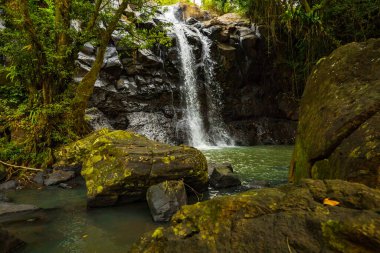 Tropik bir manzara. Yağmur ormanlarında saklı güzel bir şelale. Büyük taşlı ön plan. Macera konsepti. Doğa geçmişi. Hızlı deklanşör hızı. Sing Sing Angin Şelalesi, Bali, Endonezya