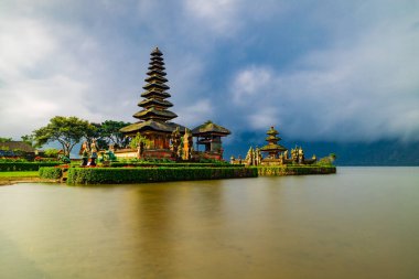 Bali adasındaki Pura Ulun Danu Bratan tapınağı. Güzel bale tapınağı. Bali 'nin simgesi. Bulutlu gökyüzü. Su yansıması. Kapama hızı yavaş. Bratan Gölü, Bali, Endonezya