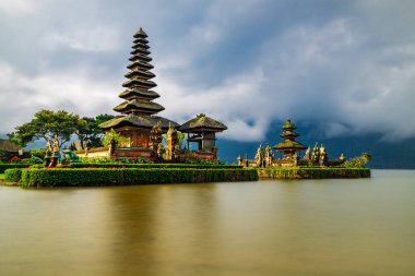 Bali adasındaki Pura Ulun Danu Bratan tapınağı. Güzel bale tapınağı. Bali 'nin simgesi. Bulutlu gökyüzü. Su yansıması. Kapama hızı yavaş. Bratan Gölü, Bali, Endonezya
