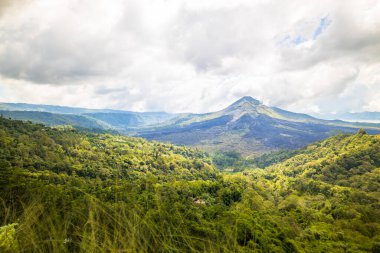 Güzel dağ manzarası. Yeşil tepeler ve Batur volkanı. Manzaralı panoramik manzara. Beyaz bulutlu gökyüzü. Kintamani, Bali, Endonezya