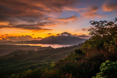 Güneş doğarken güzel bir dağ manzarası. Tepeler, Batur volkanı ve göl. Manzaralı panoramik manzara. Bulutları olan renkli bir gökyüzü. Sisli bir sabah. Kintamani, Bali, Endonezya