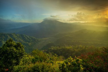 Güneş doğarken güzel bir dağ manzarası. Tepeler, Batur volkanı ve göl. Manzaralı panoramik manzara. Bulutları olan renkli bir gökyüzü. Sisli bir sabah. Kintamani, Bali, Endonezya