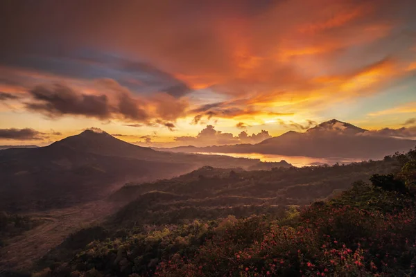 Güneş doğarken güzel bir dağ manzarası. Tepeler, Batur volkanı ve göl. Manzaralı panoramik manzara. Bulutları olan renkli bir gökyüzü. Sisli bir sabah. Kintamani, Bali, Endonezya